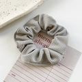 Elegant grey ribbed velvet scrunchie with pleated texture on a vintage ceramic plate - Grey