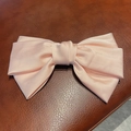 Grande pince à cheveux nœud rose pêche en satin mat sur fond de cuir texturé - Rose