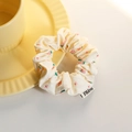 Cream-colored scrunchie with strawberry and floral prints and a fabric brand tag - Small Circle