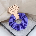 Elegant purple satin hair scrunchie with silk luster on a golden diamond card holder - Deep purple