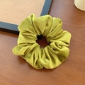 Velvet scrunchie in mustard green color on a rustic wooden table background - Yellow Green