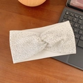 White ribbed knit twist headband with sparkling rhinestones on a wooden background - White