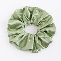 Détail macro du chouchou en satin vert clair avec des accents de strass argentés brillants - Vert clair