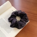 Chic black polka dot mesh scrunchie hair tie on an open book over a wooden table - Black