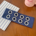 Dark blue ribbed knit headband with eight silver metal grommets on a wooden desk - Fog Blue