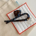 Detailed close-up of a blue tortoiseshell acetate hair claw clip with a gold logo - Lake Blue Coffee