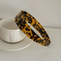 Wide tortoiseshell acetate headband resting on a white ceramic cup with soft lighting - Dark Leopard Print