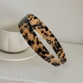 Detailed close-up of a tortoise shell acetate headband resting on white ceramic pottery - Light Leopard