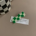 Close-up of wavy green and white checkerboard hair clip on beige leather surface - Green & Beige Checkerboard Wavy