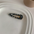 Macro detail of French retro acetate hair clip with marble pattern on ceramic tray - Black Marble Water Drop