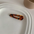 Top view of French vintage acetate hair clip with tortoiseshell pattern on white ceramic tray - Amber Leopard Water Drop