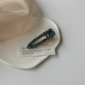 Gros plan d'une barrette à cheveux bleue à paillettes en acétate sur un plat en céramique - Goutte d'eau Noir