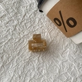 Detail view of a square leopard print acetate hair claw clip on white fabric background - Champagne