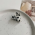 Flat lay of a cow pattern acetate hair claw clip on a ceramic tray with vintage decor - Cow Pattern