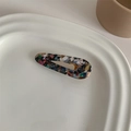 Macro shot of marble textured acetate teardrop hair clip resting on a white ceramic dish - Black Multi-color Marble Water Drop