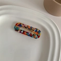 Close-up of a colorful terrazzo acetate duckbill hair clip on a white ceramic plate - Glazed Marble Square