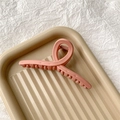 Close-up of a large matte pink shark hair claw clip with cross design on a tray - Matte Light Pink