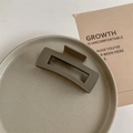Detailed close-up of a matte coffee large rectangular hair claw clip on a ceramic tray - Matte Cool Coffee