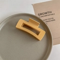 Detailed close-up of a matte mustard yellow rectangular claw clip on a grey tray - Matte Yellow