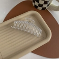 Detail of a large transparent hair claw clip with golden spring on a stylish tray - Transparent (No Paint)