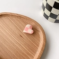 Nahaufnahme der herzförmigen Haarklammer mit rosa Karomuster auf einem Holztablett - Rosa