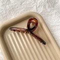 Gros plan sur la grande pince à cheveux ambrée avec design croisé et ressort en métal - Ambre Brillant