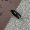 Close-up of black seamless hair clip with shiny plastic finish and silver metal base - Black