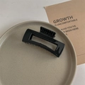 Detail of a large minimalist black square hair claw clip on a gray ceramic plate - Glossy Black