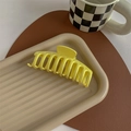 Macro view of bright yellow large hair claw clip on tray for thick hair styling - Glossy Light Yellow