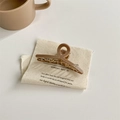 Dettaglio di un'elegante pinza per capelli minimalista beige su tessuto color crema - Caffè Chiaro Piccolo