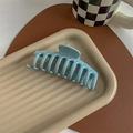 Macro detail of the light blue matte hair claw clip on a decorative striped tray - Glossy Light Blue
