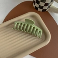 Detail of avocado green large hair claw clip on a textured tray in a lifestyle setting - Glossy Light Green