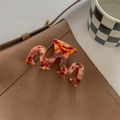 Detailed close-up of wavy amber tortoiseshell hair claw clip on a brown suede bag - Red