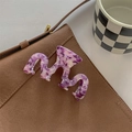 Macro detail of wave-shaped purple marble acetate hair claw clip on leather bag - Dark Purple