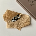 Detail einer schwarz-weißen Marmor-Acetat-Haarklammer mit einer goldfarbenen Metallbasis - Schwarz-Weiß-Textur Stil