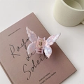Close-up of pink butterfly hair claw with pearlescent acetate texture on a book - Pink Purple