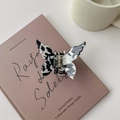 Detail der Haarklammer in Schmetterlingsform mit Kuhmuster auf einem Buch - Schwarz Weiß