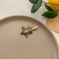 Detailed view of a star-shaped tortoiseshell hair clip on a minimalist display tray - Gold Deep Tortoiseshell