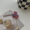 Close-up of tricolor checkered hair claw clip next to a Paris book and lemon tea - Red and Blue