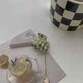 Detail view of green and white checkerboard hair claw clip among lifestyle decorations - Green