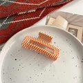 Macro-opname van een oranje geruite haarklem van acetaat op een wit decoratief bordje - Oranje Rechthoekige Stijl