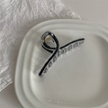 Detail view of large acrylic hair claw clip with black inlay and gold metal spring - Black
