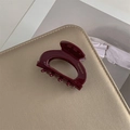 Dettaglio di elegante fermaglio per capelli in resina rosso vino con scritta dorata - Borgogna
