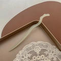 Détail d'un pic à cheveux blanc minimaliste posé sur un plateau doré avec dentelle - Branche céleste / Vert