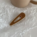 Detail of a dark brown drop-shaped hair clip with gold metal edges on a soft white background - Teardrop - Brown