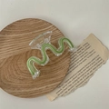 Detail shot of a wavy green hair claw clip on a wooden tray with a retro paper background - Green Wave