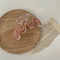 Detailed close-up of a large wave-shaped acrylic hair claw with wood-grain texture inlay - Pink Wave