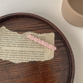 Detailansicht einer rosa Haarspange mit Marmortextur auf Vintage-Papier und Holzgrund - Hellrosa