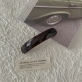 Dettaglio di fermaglio per capelli fatto a mano in acetato ambrato con scritte oro - Marrone