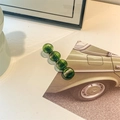 Detailed view of dark green acetate hair claw clip with vertical texture and metal base - Round Hair Clip